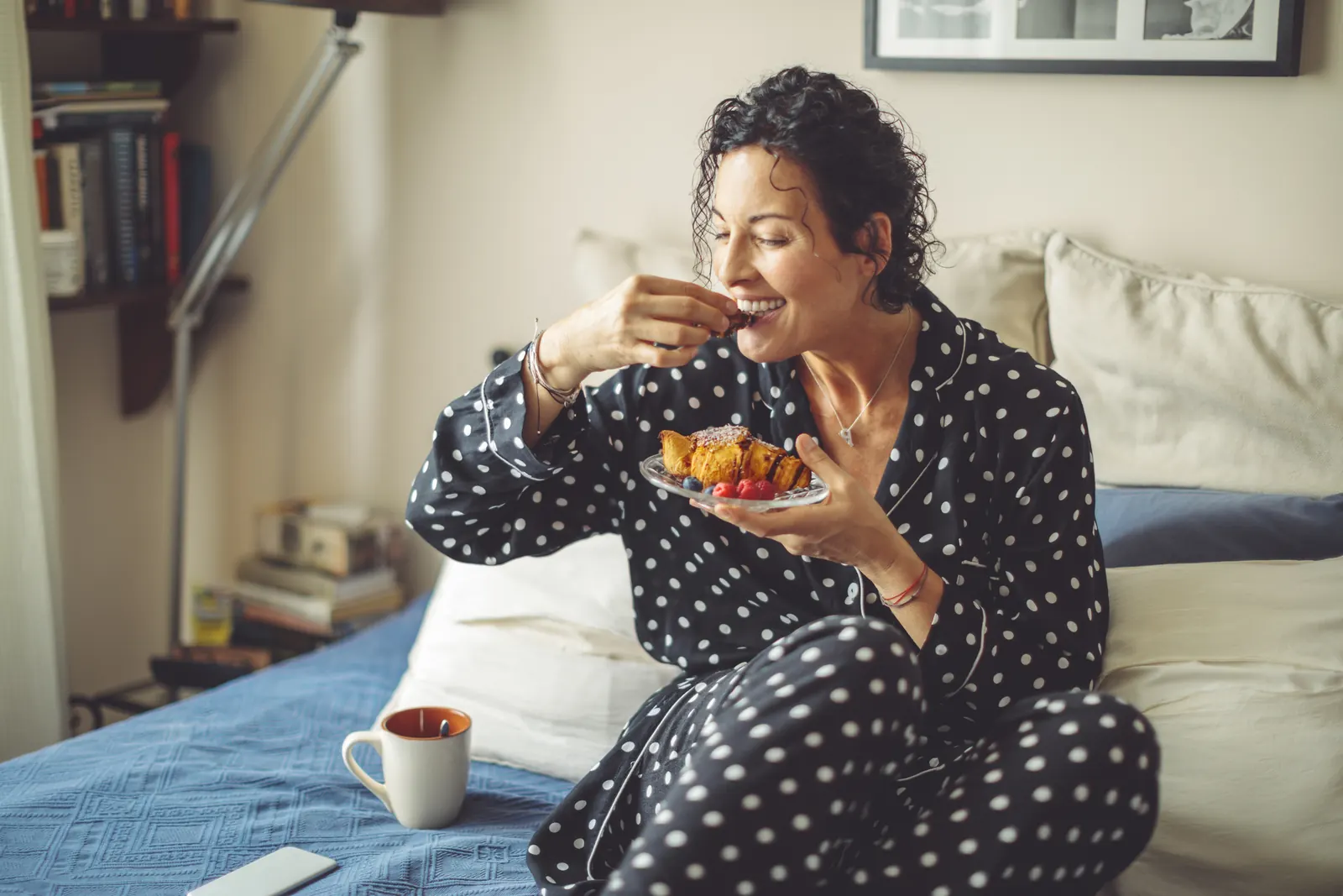 Woman sitting in bed eating a snack